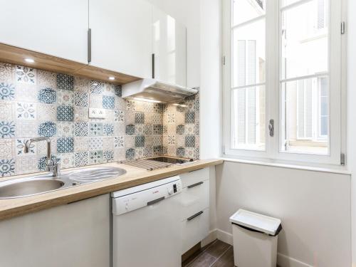 une cuisine blanche avec un évier et une fenêtre dans l'établissement L'Escapade Marseillaise T2 Moderne avec Cuisine Équipée et à 5 min du Vieux-Port, à Marseille