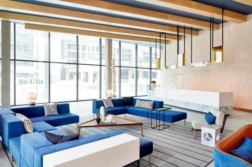 a living room with blue furniture and large windows at AC Hotel by Marriott Greenville in Greenville