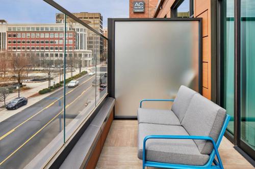 a chair on a balcony with a view of a street at AC Hotel by Marriott Greenville in Greenville
