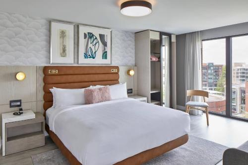 a bedroom with a white bed and a large window at AC Hotel by Marriott Greenville in Greenville