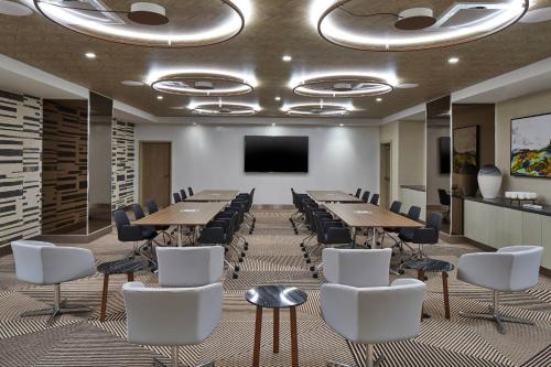 a conference room with tables and chairs and a flat screen tv at AC Hotel by Marriott Greenville in Greenville