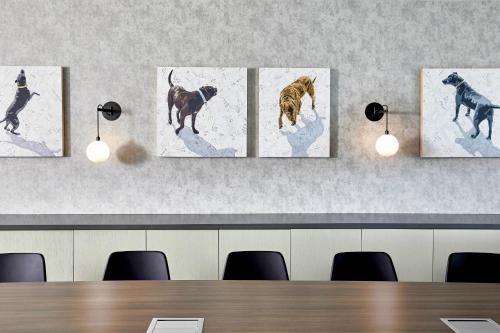 a room with four paintings of dogs on the wall at AC Hotel by Marriott Greenville in Greenville