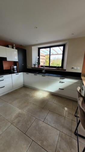 une cuisine avec des placards blancs et une grande fenêtre dans l'établissement Maison La Valdiane vue lac et montagne, à Rousset