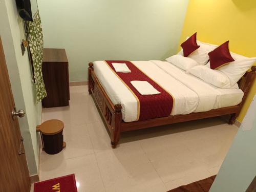 a bedroom with a bed with red and white pillows at Sathya Residency Thandarampet in Tiruvannāmalai