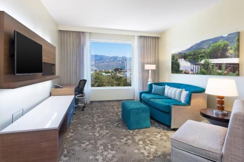 a hotel room with a blue couch and a large window at Courtyard by Marriott Kingston, Jamaica in Kingston