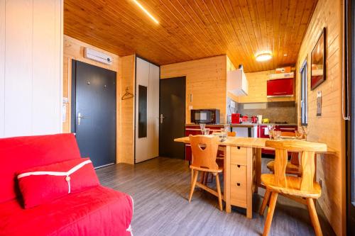 a living room with a table and a red couch at Charmant studio au cœur d une station des Vosges in Sondernach