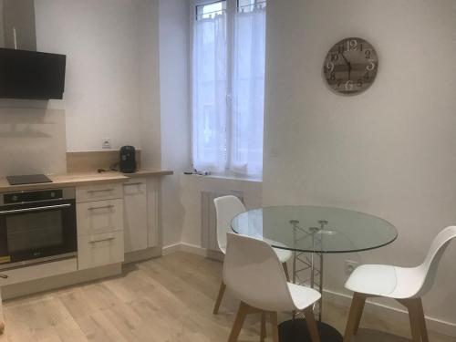 a kitchen with a glass table and white chairs at Coeur de Saint Marcellin in Saint-Marcellin