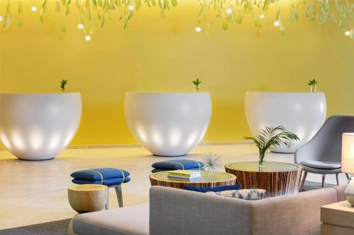 a lobby with yellow walls and chairs and tables at Renaissance Wind Creek Curacao Resort in Willemstad