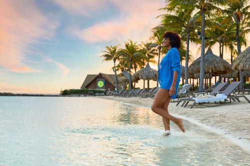 a woman walking on the beach near the water at Renaissance Wind Creek Curacao Resort in Willemstad