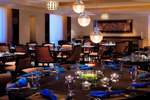 a dining room with tables and chairs and chandeliers at Courtyard By Marriott Kuwait City in Kuwait