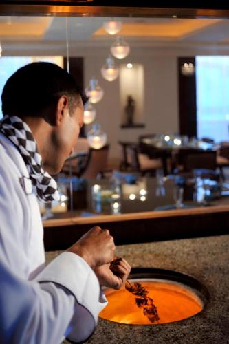 a man sitting at a bar with a plate of food at Courtyard By Marriott Kuwait City in Kuwait