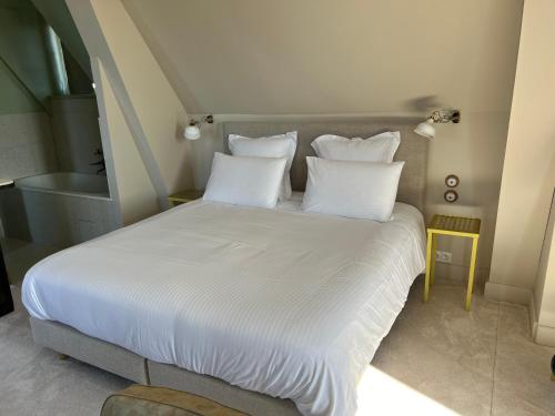 a bed with white sheets and pillows in a room at Logis Hotel La Maison à Pan De Bois in Vierzon