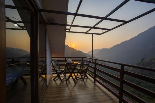 Un balcón de una casa con una mesa y sillas. en Alaya Stays Madhuram Pet-Friendly Hillside Retreat With Garden & Balcony, en Dehradun