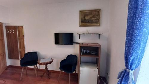 a living room with two chairs and a tv at Penzion Slunečno in Dobšín