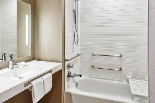 a bathroom with a sink and a tub and a toilet at AC Hotel by Marriott Cincinnati at The Banks in Cincinnati