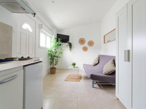 Il comprend une cuisine et un salon avec un canapé violet. dans l'établissement Studio avec jardinet, à Martigues