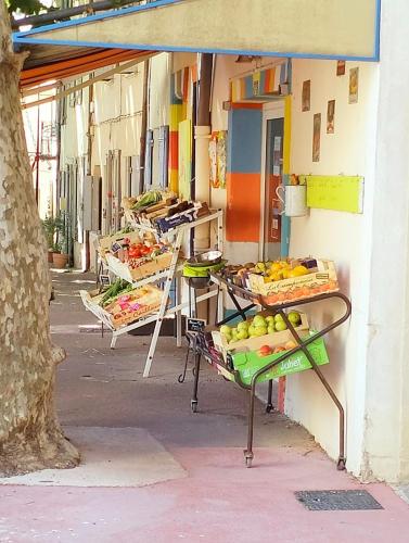 un groupe de tables avec des fruits sur le trottoir dans l'établissement La Cigale bleue, à Villes-sur-Auzon