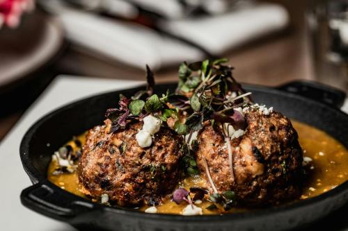 a pan with two meatballs in a bowl of food at Renaissance Dallas at Plano Legacy West Hotel in Plano