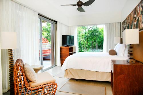 a bedroom with a bed and a tv and a window at El Mangroove Papagayo, Autograph Collection in Papagayo, Guanacaste