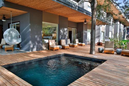 a pool on a wooden deck with chairs and a house at El Mangroove Papagayo, Autograph Collection in Papagayo, Guanacaste