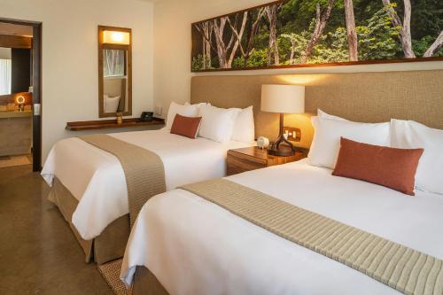 a hotel room with two beds and a bathroom at El Mangroove Papagayo, Autograph Collection in Papagayo, Guanacaste