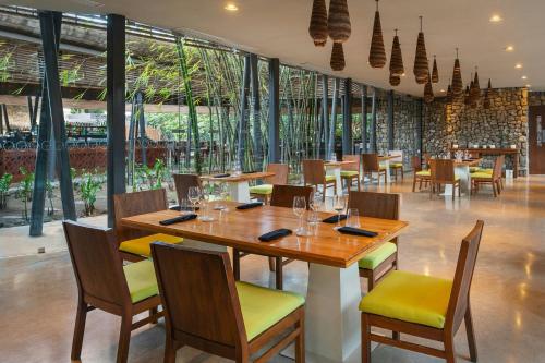 a restaurant with wooden tables and chairs and windows at El Mangroove Papagayo, Autograph Collection in Papagayo, Guanacaste