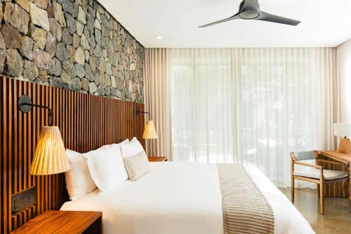 a bedroom with a large white bed and a desk at El Mangroove Papagayo, Autograph Collection in Papagayo, Guanacaste