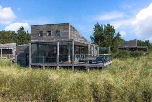 a house sitting on top of a grassy hill at Luxe Villa met Uitzicht 4p - Luxe, Rust & Water - Villa 67 in Ouddorp