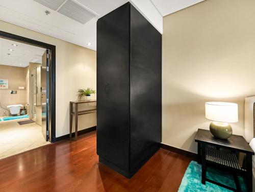 a large black wall in a living room with a lamp on a table at Luxury Apartments in Anantara Resort with Stunning Burj AlArab & Sea Views in Dubai