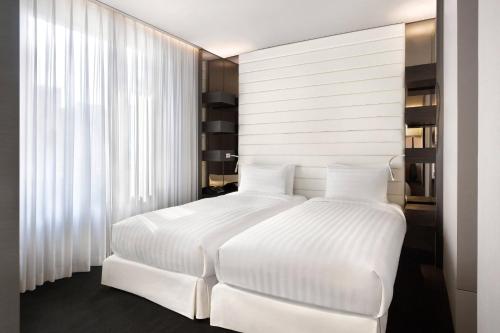 a bedroom with a white bed with white sheets at THE PLAZA Seoul, Autograph Collection in Seoul
