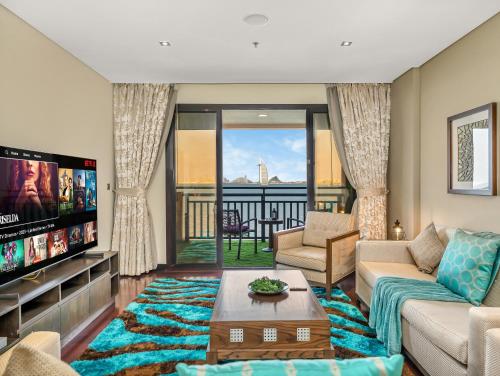 a living room with a couch and a tv at Luxury Apartments in Anantara Resort with Stunning Burj AlArab & Sea Views in Dubai