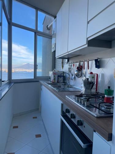Una cocina con gabinetes blancos y un horno de estufa. en Panoramico a Posillipo, en Nápoles