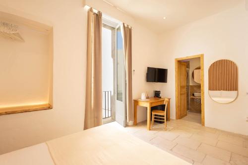 a room with a bed and a desk and a window at Palazzo Kapece in Monopoli