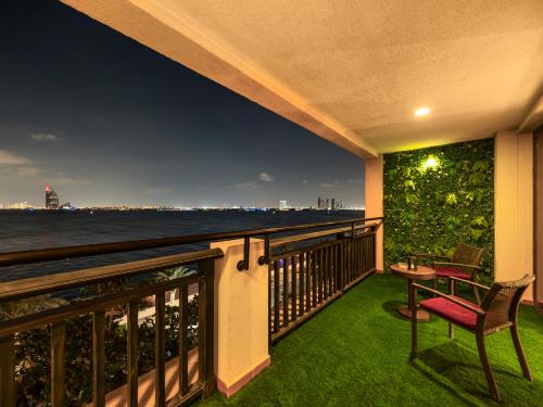 a balcony with a view of the ocean at night at Luxury Apartments in Anantara Resort with Stunning Burj AlArab & Sea Views in Dubai