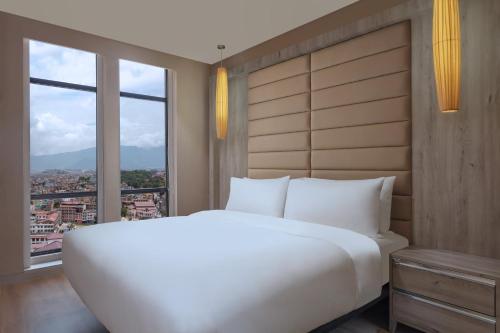 a large white bed in a room with a window at Aloft Kathmandu Thamel in Kathmandu