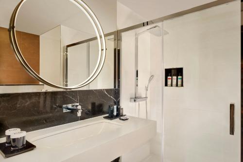 a white bathroom with a sink and a mirror at Montcalm East, Autograph Collection in London