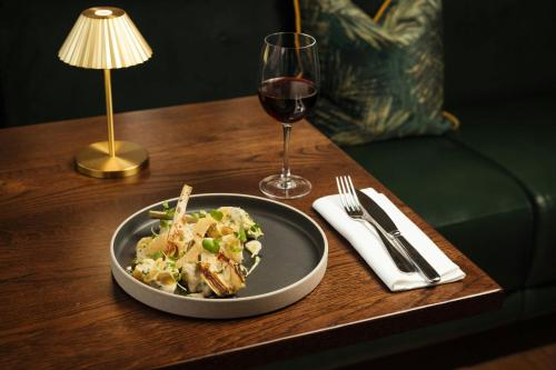 a plate of food and a glass of wine on a table at Montcalm East, Autograph Collection in London