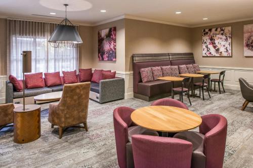 a waiting room with a couch and tables and chairs at Courtyard Clemson in Clemson