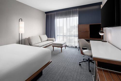 兰辛Courtyard by Marriott Lansing Downtown的配有床和书桌的酒店房间