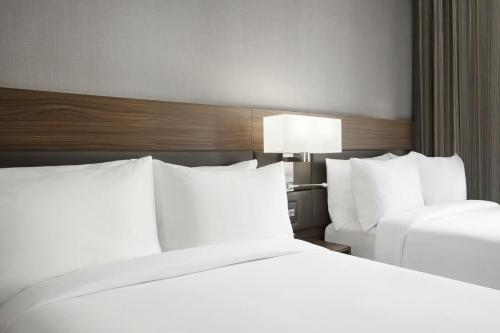 a hotel room with two beds with white pillows at AC Hotel by Marriott St. Louis Clayton in Clayton