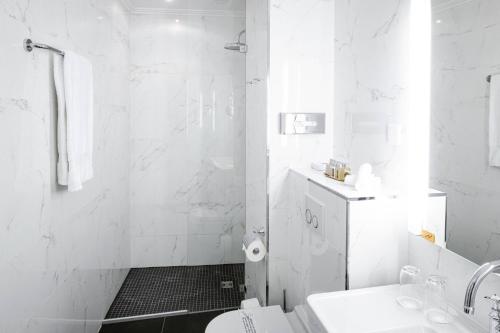 a white bathroom with a toilet and a shower at Grand Hotel Suisse Majestic, Autograph Collection in Montreux