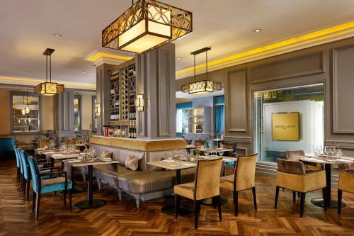 a restaurant with tables and chairs and a chandelier at The College Green Dublin Hotel, Autograph Collection in Dublin