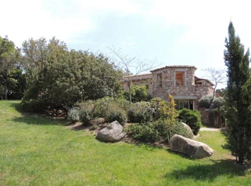 une grande maison en pierre avec des rochers dans une cour dans l'établissement figuier 2 - 1 chambre & piscine - 5 mn plage, à Zonza