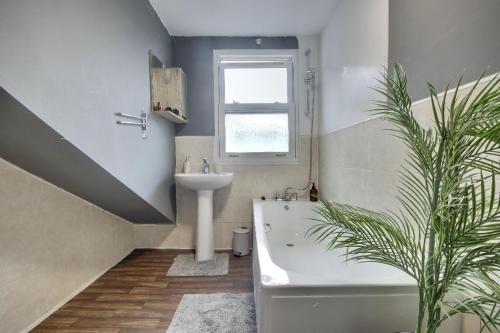 a bathroom with a white tub and a sink and a plant at Top Floor Apartment in Portsmouth