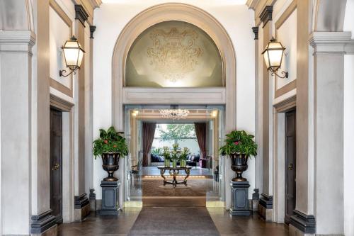 an ornate hallway with two pillars with plants on them at Sina Villa Medici, Autograph Collection in Florence