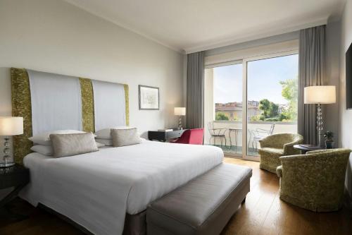 a bedroom with a large white bed and a balcony at Sina Villa Medici, Autograph Collection in Florence