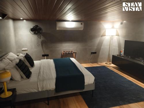 a bedroom with a large bed and a television at StayVista at Sasha Farms in Roha with Pool, WiFi in Roha