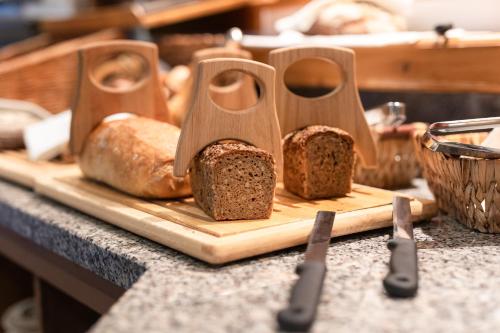 a loaf of bread on a cutting board with spoons at Hotel Garni Angela in Ischgl