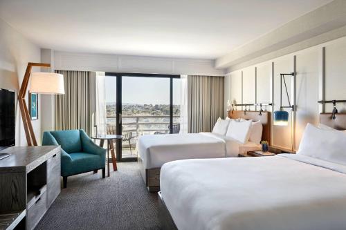 a hotel room with two beds and a chair at Westdrift Manhattan Beach, Autograph Collection in Manhattan Beach