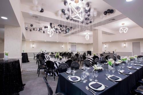 a banquet hall with long tables and black chairs at Westdrift Manhattan Beach, Autograph Collection in Manhattan Beach